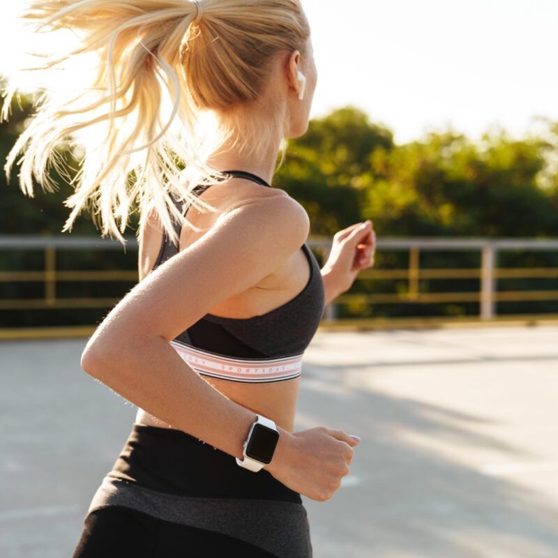Runner wearing a smartwatch jogging outdoors near The 208 in Boise, ID